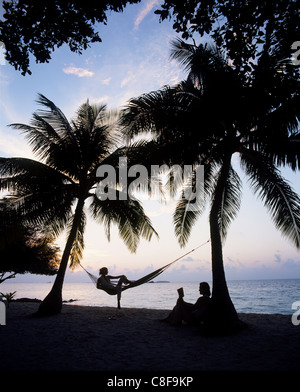 Giovane relax su una spiaggia al tramonto, Maldive, Oceano Indiano Foto Stock