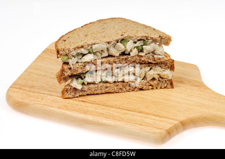 Insalata di pollo in sandwich di pane integrale impilati sul taglio del legno di bordo su sfondo bianco. Foto Stock