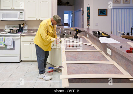 L'uomo costruisce un modello in legno per impiego nella realizzazione del nuovo piano in granito sostituzioni per cucina residenziale Foto Stock