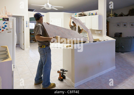 Due uomini sollevare Formica bancone da armadi in cucina moderna durante un progetto di ristrutturazione Foto Stock