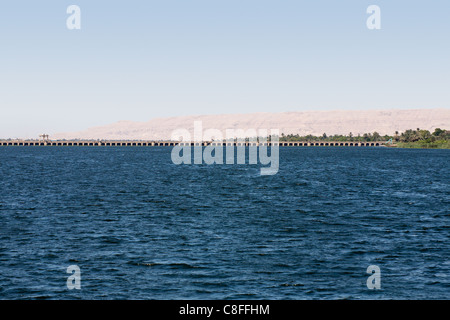 Il fiume Nilo in primo piano con Esna barrage all'orizzonte e molto distanti desert mountain range dietro, Egitto, Africa Foto Stock