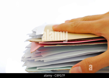 La mano su di una pila di file piena di documenti a significare concetti come il lavoro e lo stress e la vita di lavoro e oggetti business. Foto Stock