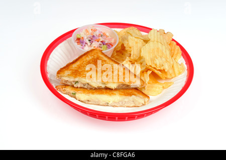 Tostare sandwich tunamelt con coleslaw e potato chips su carta bianca piastra in plastica rosso cesto su sfondo bianco ritaglio. Foto Stock