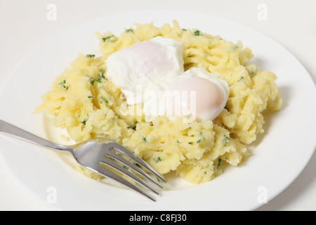 Una rapida ed economica pasto a base di uova in camicia in un nido di purè di patate con prezzemolo Foto Stock