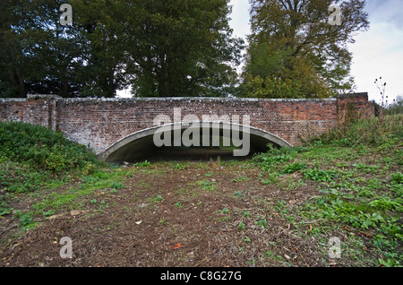 Un fiume secco in autunno mostra incrinato il fango. Il ponte dà un'idea di quanto sia profonda l'acqua dovrebbe essere. Foto Stock