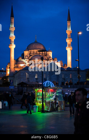 Venditore ambulante di notte con vividamente illuminata in stallo al di fuori della Nuova Moschea, Istanbul, Turchia con persone che camminano da. Foto Stock