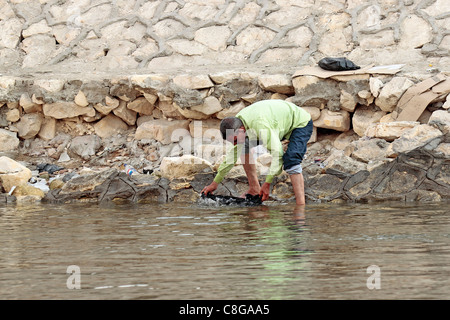 L'uomo il lavaggio della biancheria sulla banca del fiume Nilo al Cairo Foto Stock