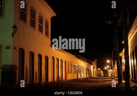 Paraty, Brasile. Gli edifici coloniali nel villaggio di notte con artificiali di illuminazione stradale e di una bicicletta. Foto Stock