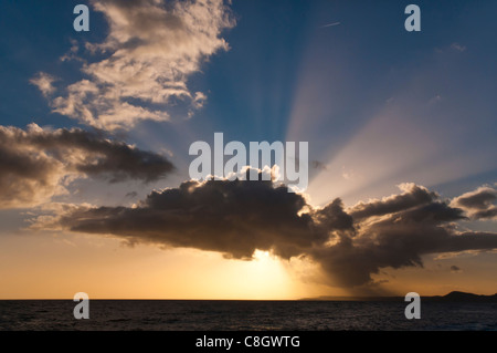 Nuvole drammatico e impostazione di sole sulla spiaggia di Devon Foto Stock