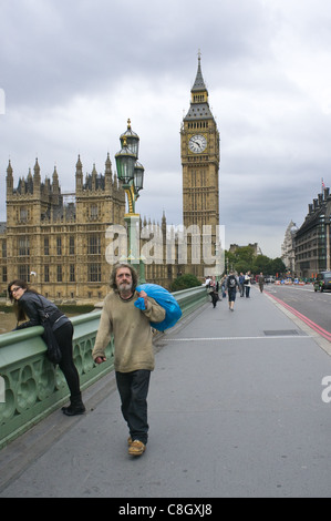 Un uomo, eventualmente senzatetto, porta un sacco di fronte Westminster Bridge, Londra Foto Stock