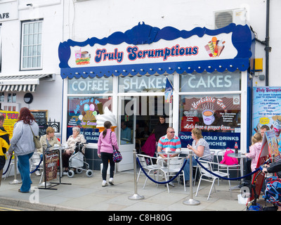 Turisti che si godono una sosta e ristoro presso i tavoli fuori una piccola caffetteria in Whitby North Yorkshire Foto Stock