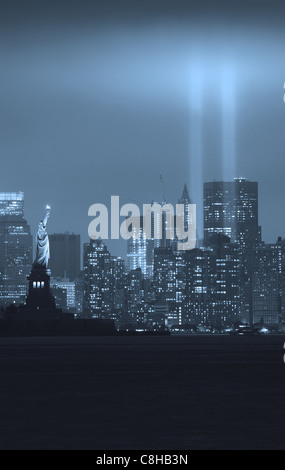 New York City Manhattan skyline del centro in bianco e nero di notte con la statua della libertà e i fasci di luce Foto Stock