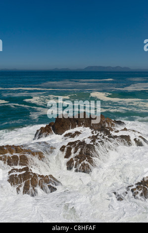 La frantumazione delle onde sui massi lungo il percorso 44 Table Mountain in background in Sud Africa Foto Stock