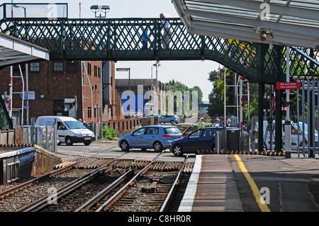 Auto e persone che attraversano passaggio a livello dopo che il treno ha tirato nella stazione di Chichester Foto Stock