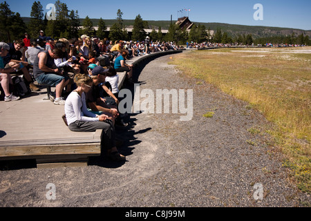 Le persone sono in attesa di ricevere il geyser Old Faithful eruzione al Parco Nazionale di Yellowstone Wyoming USA Foto Stock