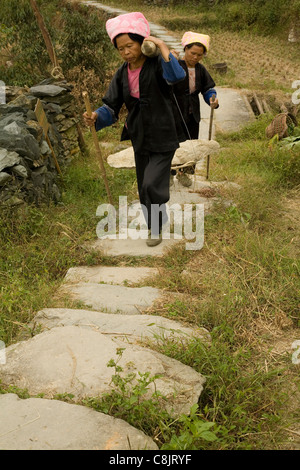 Portando un heavy rock di un edificio sito in un villaggio in Cina vivono in colline di Cina circondato da campi di riso. Foto Stock
