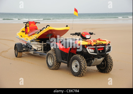 Cornovaglia, Inghilterra. Un bagnino RNLI quad bike e jet ski PWC mezzo di salvataggio su di una spiaggia di sabbia. Foto Stock