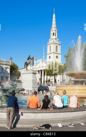 Persone immergendo i piedi nella fontana, Trafalgar Square, Londra, Inghilterra Foto Stock