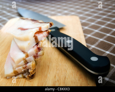 Domestico di pancetta a fette e un coltello sul tavolo. Foto Stock