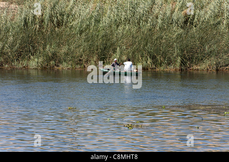 Due uomini la pesca vicino ad una banca a lamelle sul fiume Nilo in Egitto Foto Stock
