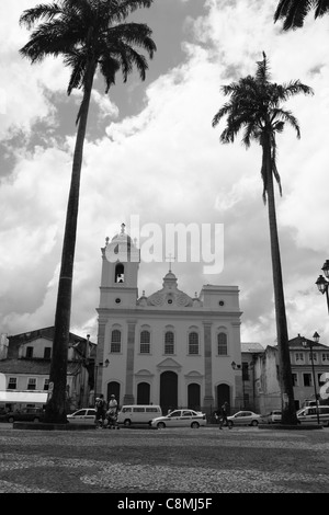 Una chiesa nel centro di Salvador de Bahia, con una torre campanaria mancante. Due palme a fare da cornice alla vista. Foto Stock