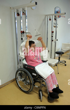 Una donna su una sedia a rotelle facendo esercizi di riabilitazione fisica in ospedale è la fisioterapia palestra Foto Stock