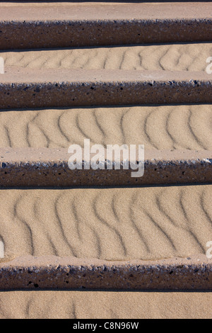 I modelli in sabbia drifting sui passi concreti che conducono in basso verso la spiaggia di Blackpool, Regno Unito Foto Stock