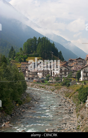 L'Italia, Piemonte, il Parco Nazionale del Gran Paradiso, Cretaz, vista del flusso e villaggio nel paesaggio di montagna Foto Stock