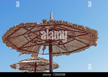 Acciaio a bordo piscina e reed ombrellone/parasol contro il cielo blu chiaro Foto Stock