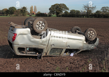 Una trazione a 4 ruote motrici non riesce a negoziare una curva su una strada di campagna e finisce sul suo tetto in un campo Foto Stock