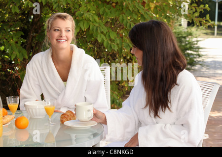 Due giovani donne breakfasting sul patio Foto Stock
