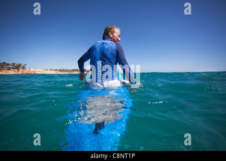 Uomo caucasico galleggiante sulla tavola da surf Foto Stock