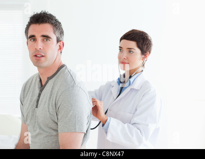 Medico di esaminare il suo paziente con uno stetoscopio Foto Stock