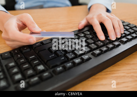 La donna la digitazione sulla tastiera in possesso di una carta di credito Foto Stock