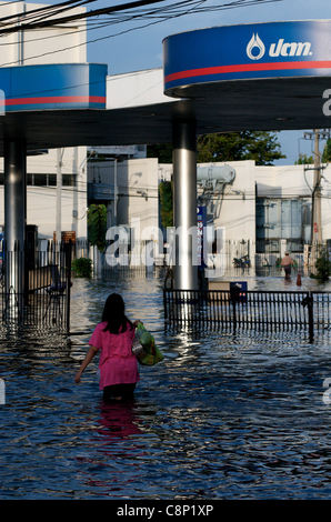 La donna thailandese cammina nelle acque alluvionali vicino a una stazione di servizio, Phahon Yothin Road, Bangkok, Thailandia, Sud-Est asiatico il 28 ottobre 2011. La Thailandia sta vivendo le sue peggiori inondazioni in 50 anni. Crediti: Kraig Lieb Foto Stock