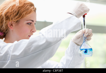 Science Student mettendo gocce di blu in un liquido Foto Stock