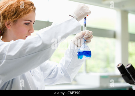 Carino science student mettendo gocce di blu in un liquido Foto Stock