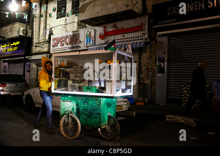 L'uomo spingendo un carrello decorato con la figura di un militante Paletinian a Ramallah una città Palestinese nella zona centrale di West Bank nei territori palestinesi Foto Stock