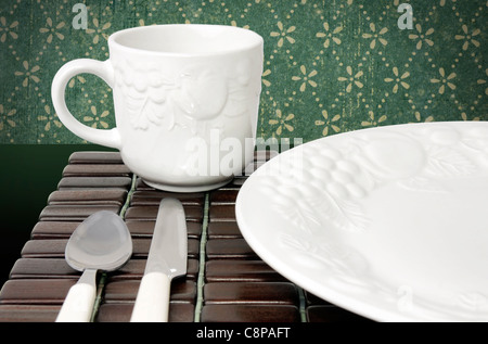 Cena impostazione della piastra in porcellana bianca su legno scuro e tappeto verde carta da parati vintage Foto Stock