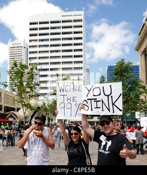 "Noi siamo il 99%' anti-capitalismo manifestanti a occupare la protesta di Perth vicino ad un uomo di mangiare una multinazionale per una catena di fast food Burger. Foto Stock