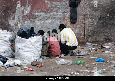 Gli uomini stringersi intorno al fumo eroina a Delhi. L'abuso di droga in India è in aumento, soprattutto nelle grandi aree urbane. Foto Stock