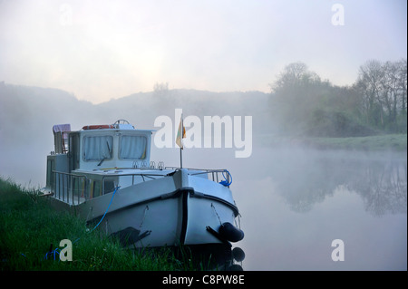 Una chiatta ormeggiata in early morning mist sul fiume Yonne in Borgogna, Francia Foto Stock