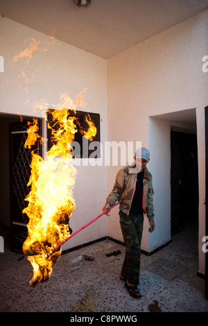 Ribelle in Sirt bruciare le bandiere del governo che hanno trovato in una casa essendo utilizzato da Gheddafi come un nascondiglio Foto Stock