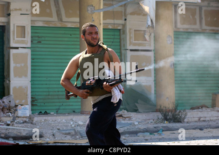 Rebel fighter battaglie cecchini nella piazza occupata dalle forze di Gheddafi sul finale il giorno della liberazione di Zarwiya Foto Stock