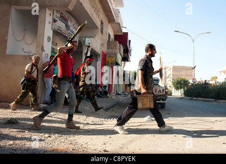 Rebel fighter battaglie cecchini nella piazza occupata dalle forze di Gheddafi sul finale il giorno della liberazione di Zarwiya Foto Stock