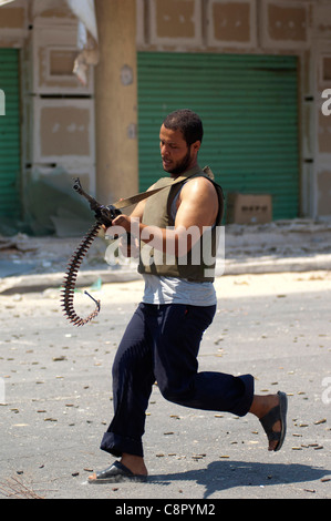 Rebel fighter battaglie cecchini nella piazza occupata dalle forze di Gheddafi sul finale il giorno della liberazione di Zarwiya Foto Stock