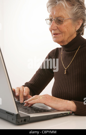 Donna anziana digitazione sul suo computer portatile. Foto Stock