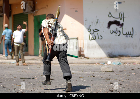 Rebel fighter battaglie cecchini nella piazza occupata dalle forze di Gheddafi sul finale il giorno della liberazione di Zarwiya Foto Stock