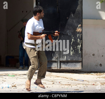 Rebel fighter battaglie cecchini nella piazza occupata dalle forze di Gheddafi sul finale il giorno della liberazione di Zarwiya Foto Stock