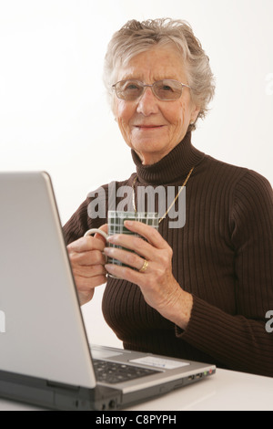 Un'anziana donna che utilizza un computer portatile. Foto Stock